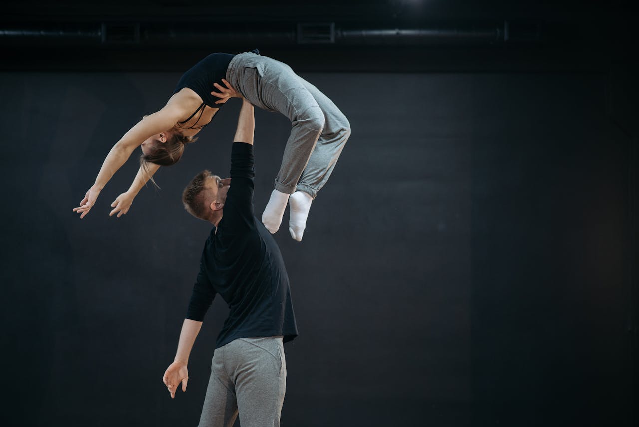 Man and woman performing a dynamic acrobatic lift in dance.