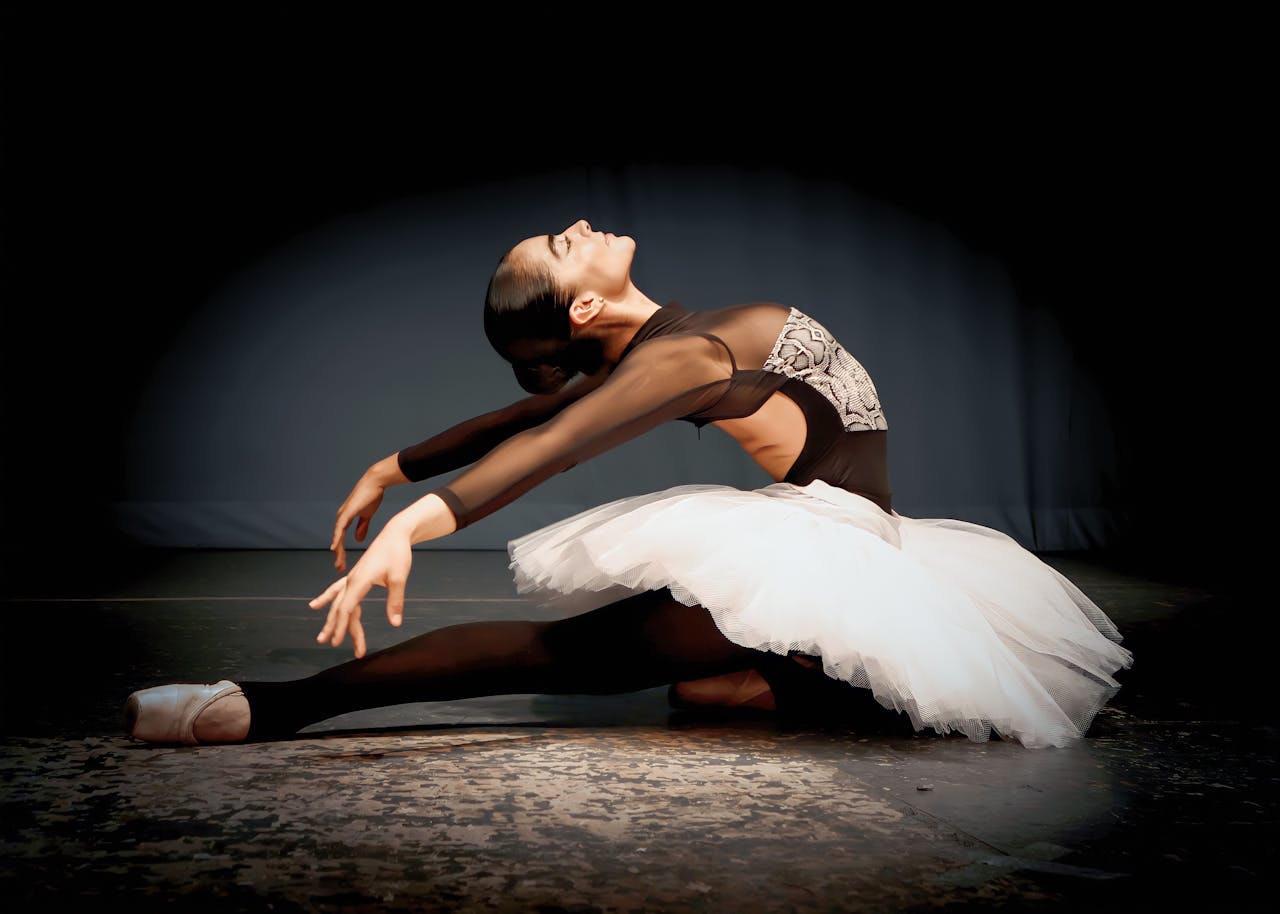 Ballet dancer performing gracefully on stage in elegant attire with a dramatic pose.